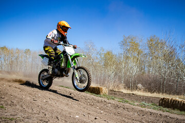 A kid rides his dirt bike on a track.