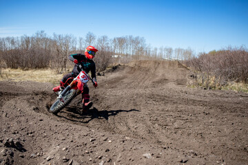 Dirt bike rider enters a corner after landing a jump on a motocross track.