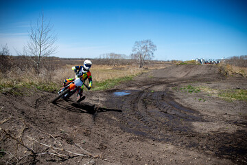 Moto X rider entering a corner.  Puddle of water ont rack.