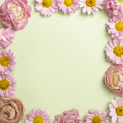 Pink flowers frame on light green background. top view, copy space