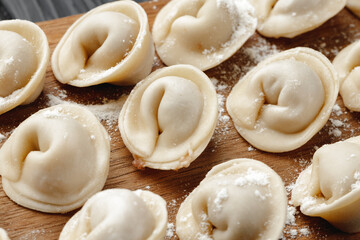 Raw meat dumplings on wooden board on table