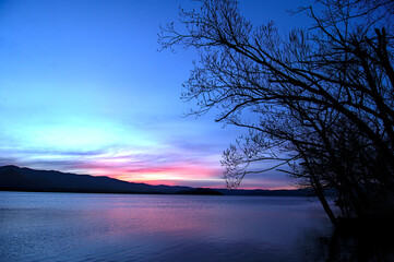 鮮やかな色彩の黄昏の空と湖畔の樹木の影。日本の北海道の屈斜路湖。
