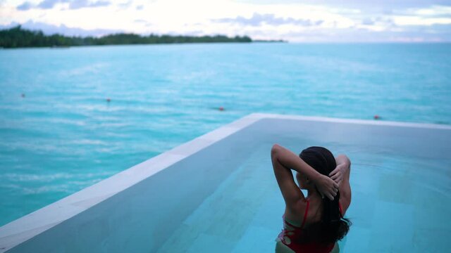Luxury swimming pool resort paradise summer destination woman relaxing in infinity pool at hotel idyllic turquoise ocean background holiday. Panoramic banner.