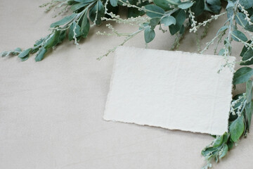 Photostock wedding styled composition. Feminine desktop mockup scene with eucalyptus leaves, silk ribbon, blank greeting card on creme textured concrete background. Flat lay, top view.