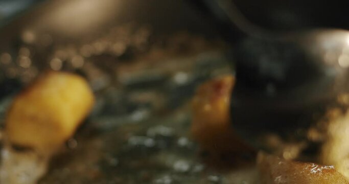 The chef glazes fried banana pieces with caramelized butter in a hot skillet