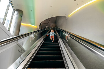 Little girl running up the escalator in shopping mall