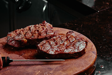 Grilled steak on a wooden board. Chef measures the temperature of fried steak Ribeye in the restaurant. Fermented steak. 
