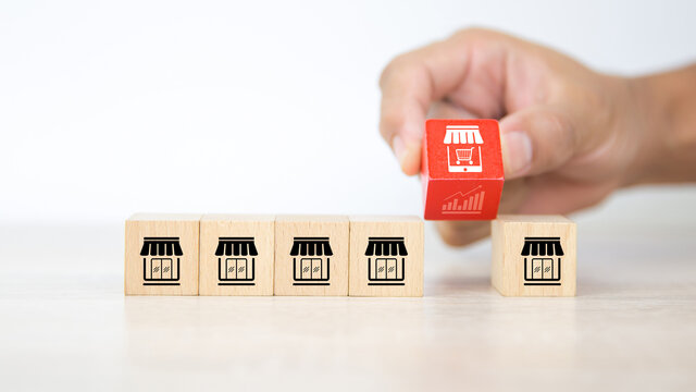Franchise, Hand choosing cube wooden blocks stack with franchise business store E-commerce smartphone with graph icon for business growth and change to online financial marketing concepts.