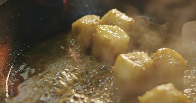 The chef adds cognac to fried banana slices in sizzling oil in a hot skillet and fire it up