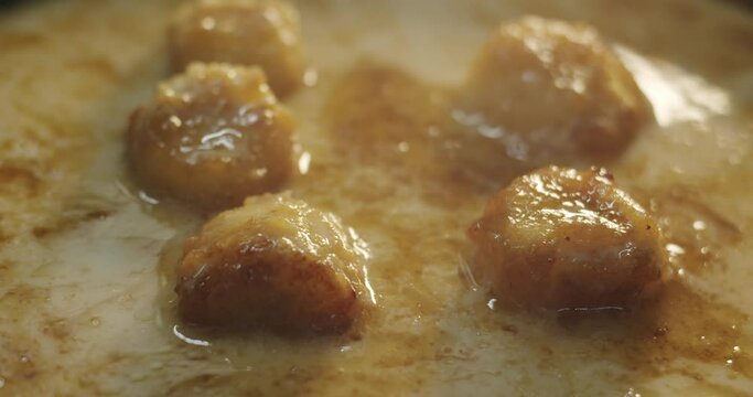 Caramelized banana chunks gurgle and boil in hot coconut milk and caramel sauce in a hot skillet