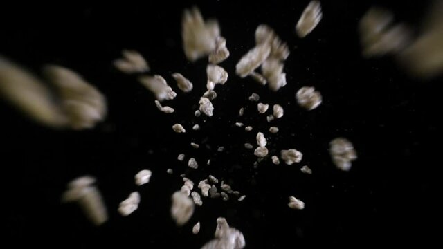 Brown Chocolate cereal crispy flakes fall into frame against black background in slow motion  