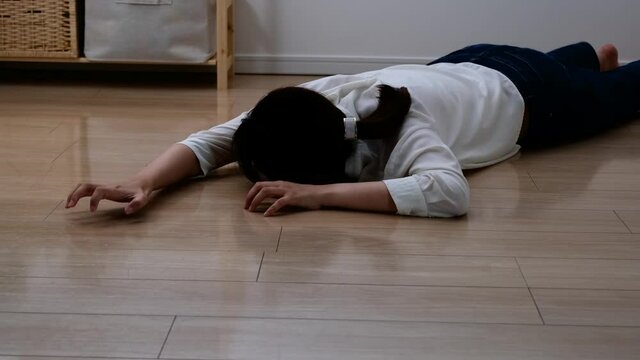 床に倒れ込んで苦しそうにする女性