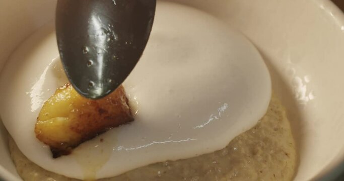 Pieces of caramelized fried banana are added with a tablespoon on top of the coconut mousse cream