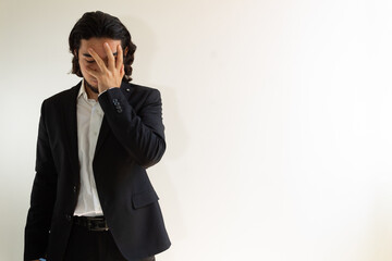 Hispanic man with long hair and a black suit frustrated on a white background