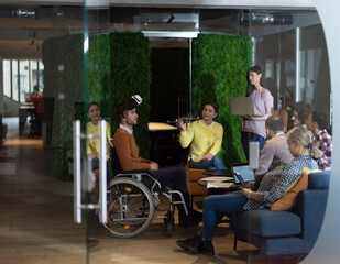 Disabled businessman in a wheelchair at work in modern open space coworking office with team using virtual reality googles drone assistance simulation
