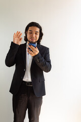 Hispanic man in black suit using a smartphone on a white background