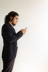 Hispanic man in black suit using a smartphone on a white background