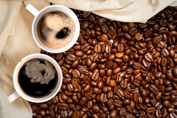 Cup of coffee with beans on table, top view