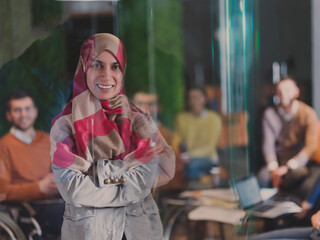 Fototapeta premium Muslim woman wearing hijab in office, Arabic business woman covered with headscarf smiling. Successful Arab businesswoman in modern office.