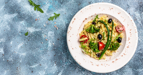 Vegan Pasta salad with tomato, broccoli, black olives, and asparagus. Healthy and detox food concept. Long banner format, top view