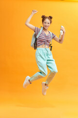 Fototapeta na wymiar Happy Asian female student jumping on yellow background