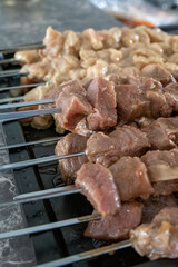 Row Shish kebab refers to seasoned cubes of meat grilled on a skewer.on black white marmor table.