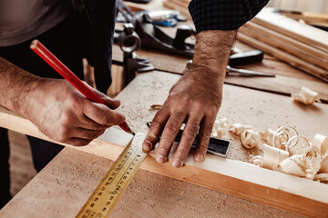 Carpenter makes pencil marks on a wood plank