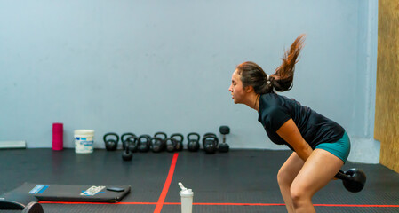Portrait of sportswoman working out her arms with a kettle bell. Hard training.