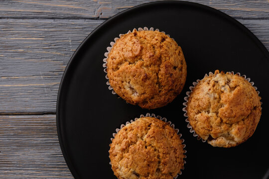 Gentle and fragrant mafins with frozen plum on a black plate on the old wooden table