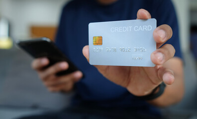 Close up view man using smart phone and holding credit card.