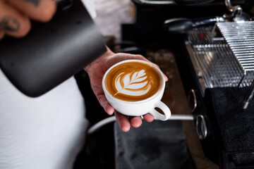 close up view  preparing a coffee by drawing a flower with milk