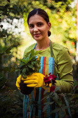 Woman working in the garden. Holding a plant. Garden beautification.