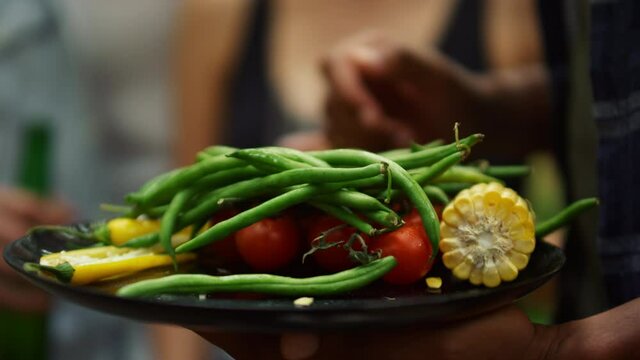 Closeup french beans, tomatoes, peppers and corn outside. Man holding plate