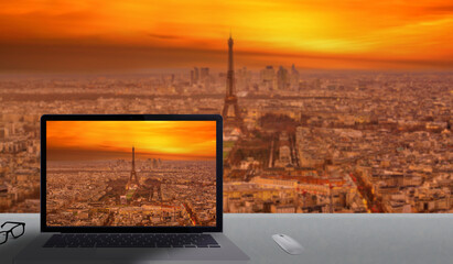 Paris viewed from a sky bar during the sunset with focus on the duplicated image inside the laptop screen
