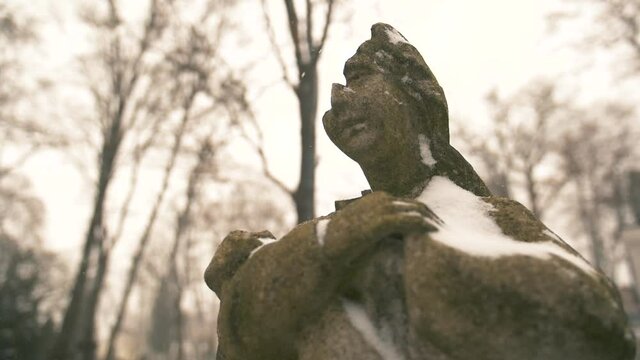  Maria statue with broken head in a snowy winter day at the Bernardine XIX century cemetery. Vilnius, Lithuania, 2019.