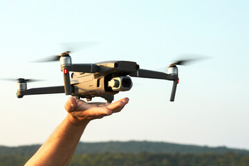 The drone lands on the outstretched arm. Selective focus. Copy space.