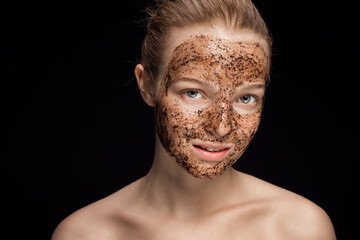 Skin scrub Coffee grounds mask on the face of a beautiful young woman Organic natural cosmetology dark studio background Isolate