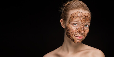 Skin scrub Coffee grounds mask on the face of a beautiful young woman Organic natural cosmetology dark studio background Isolate