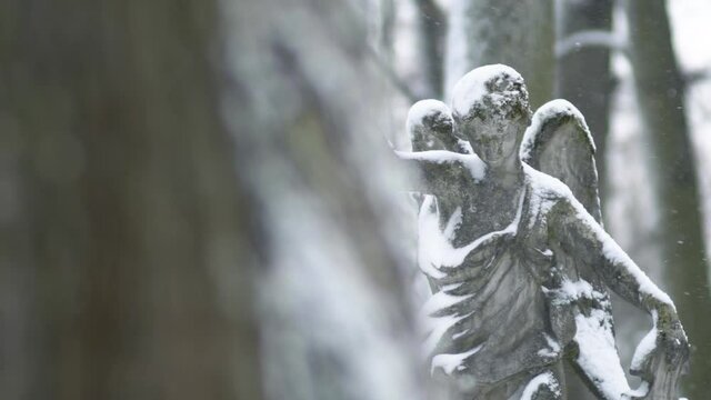 Angel statue in a snowy winter day at the Bernardine XIX century cemetery. Slow motion. Vilnius, Lithuania