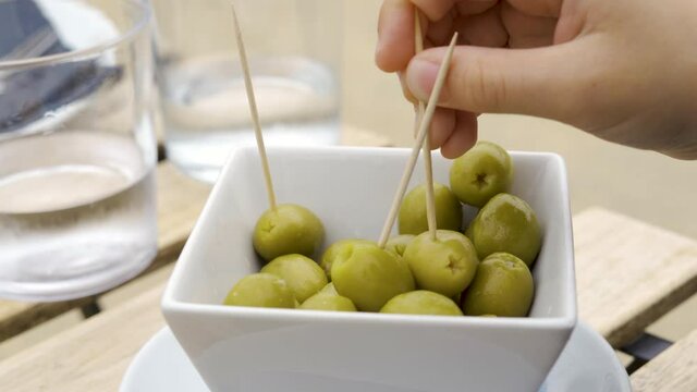 Kid eating stuffed green olives Tapa with toothpick.