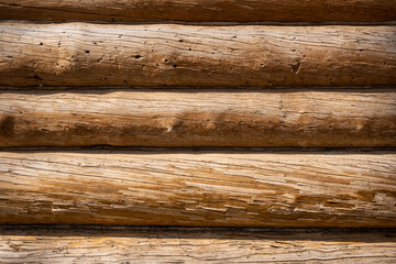 Ancient wall of old cracked wooden logs. Historical country background.