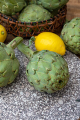 Fresh ripe green artichokes heads with yellow lemons ready to cook