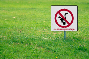 A warning sign with texts in Khmer "No pets allowed on this lawn"