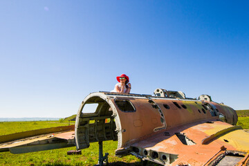 Beautiful women with red hat, sunglasses and suitcase near abandoned Soviet union army jet