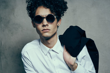 portrait of a curly-haired guy in a shirt with a jacket on his shoulder and glasses on his face