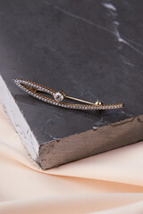 Diamond brooch on pastel silk background, close-up.