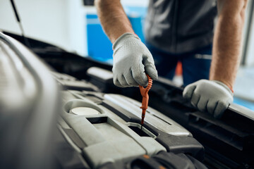 Close-up of mechanic examining car oil  at auto repair shop.