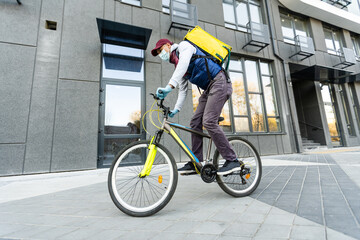 yellow thermal backpack and bicycle in the city. Food delivery service concept.