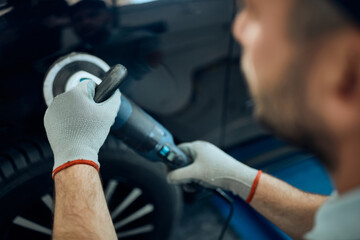 Close-up of mechanic polishing car while working in a workshop.
