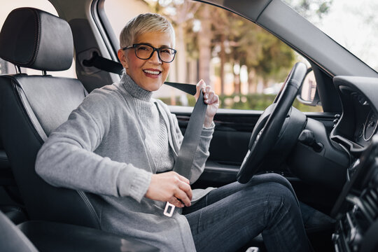Portrait of a smiling senior woman preparing for a drive, looking at camera.